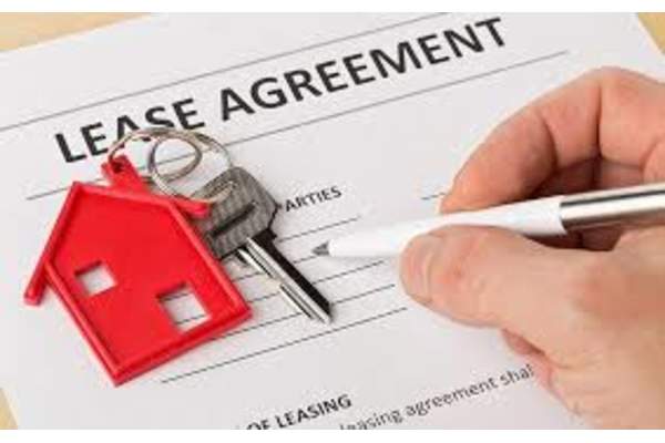A hand is signing a lease agreement with a house keychain on top. at The Revival, Salt Lake City
